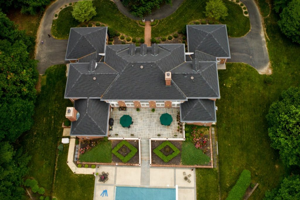 Large mansion style home with outside patio, pool, and garden topiaries